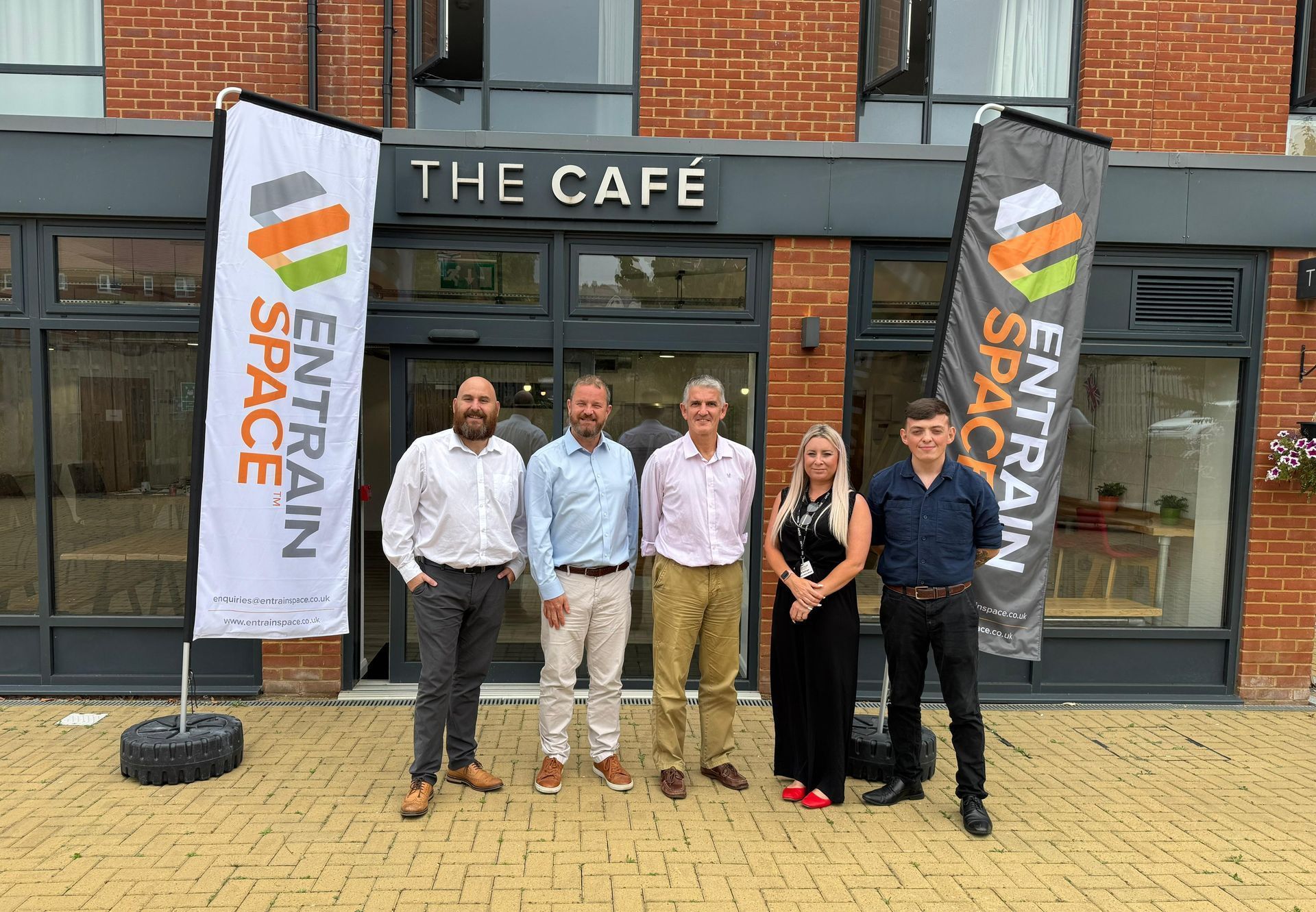 Staff outside The Café at Erskine House with Entrain Space banners